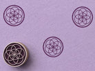 Hand carved wooden printing block featuring an overlapping sacred circle geometry motif stamped repeatedly on lavender paper.