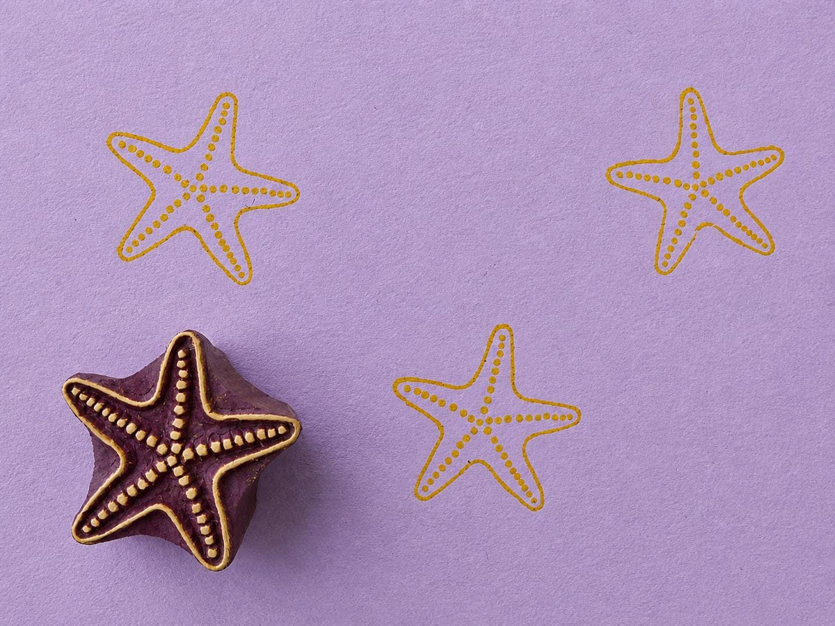 Hand carved Indian wooden block featuring coastal sea star motif printed in mustard yellow on lavender background for textile printing, pottery, clay, and paper crafts.