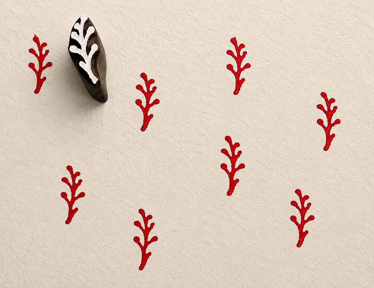 Tiny hand carved berry stem block stamp with repeating red botanical branch impressions on textured paper
