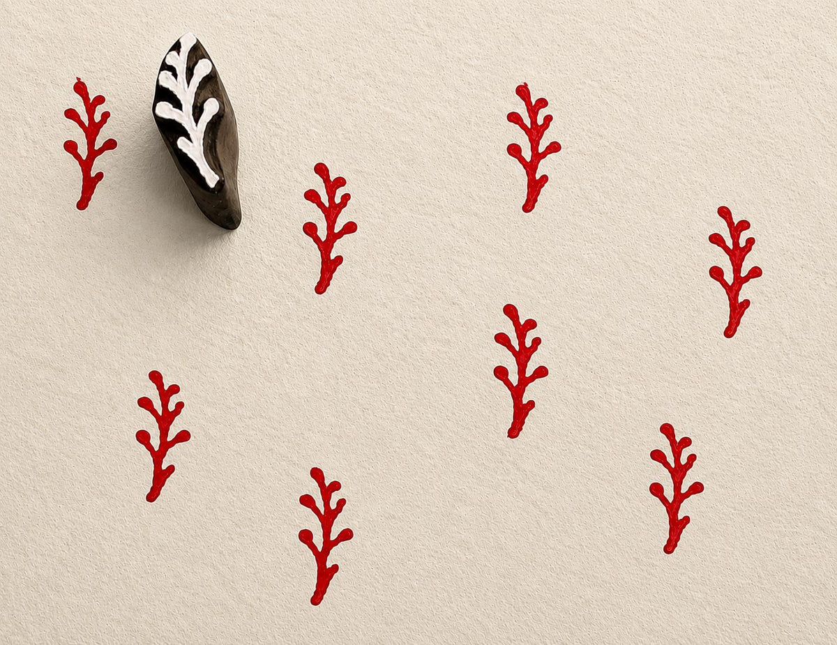 Tiny hand carved berry stem block stamp with repeating red botanical branch impressions on textured paper