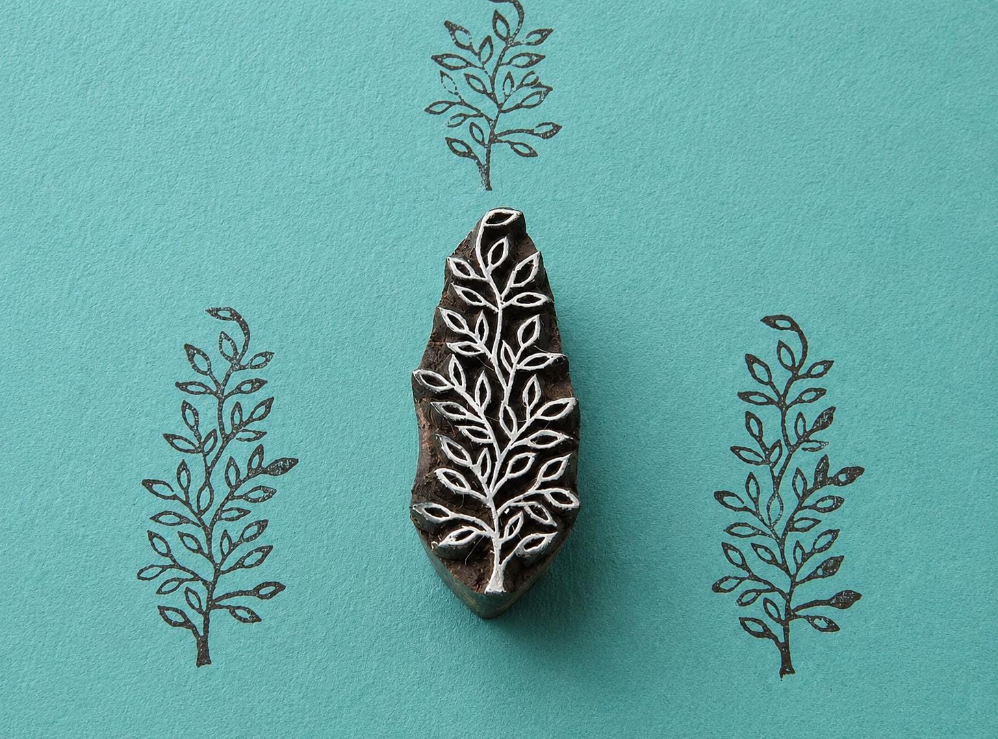 Hand carved Indian wooden block featuring delicate wild branch botanical pattern printed in black on turquoise background for textile printing, pottery, clay, and paper crafts.