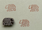 Hand carved bear block stamp creating repeating folk art impressions on handmade paper