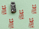 Hand carved fox printing block shown with repeating red fox impressions on handmade green paper.
