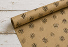 Hand stamped kraft wrapping paper featuring repeating Winter Star snowflake impressions created with a hand carved wooden block stamp.
