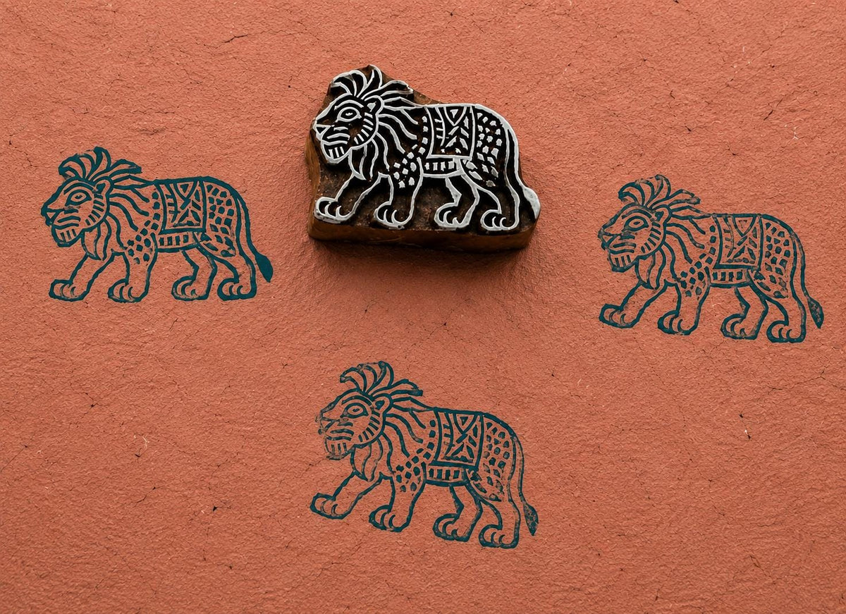 Hand carved lion block stamp with folk art details creating teal impressions on terracotta handmade paper.