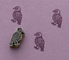 Hand carved folk songbird stamp creating plum coloured impressions on textured handmade paper.