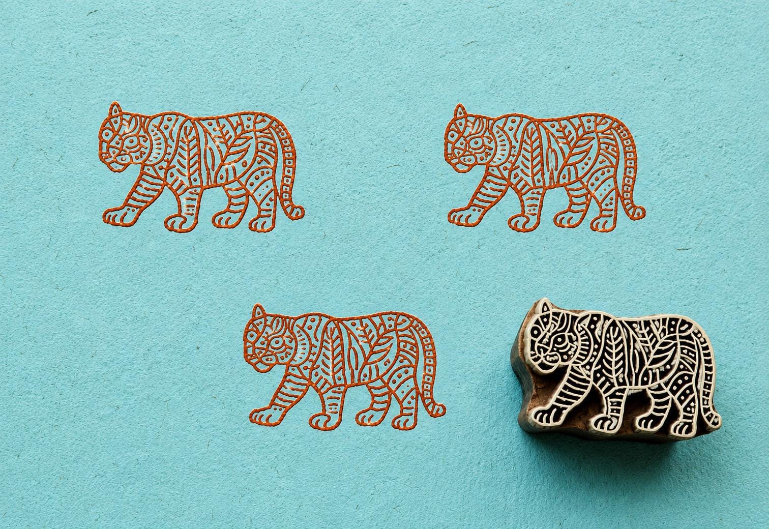 Hand carved Jungle Tiger wood block stamp with orange tiger impressions on handmade blue paper
