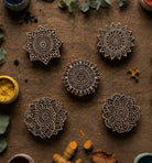 Set of five hand carved mandala wooden printing blocks arranged with natural dyes and botanical elements on rustic wood