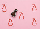 Minimal pear shaped wooden printing block stamped in coral red ink on pink background for fabric printing, wrapping paper, pottery, and handmade crafts.