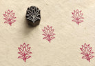 Hand-carved wooden printing block featuring a lotus blossom motif stamped in pink ink on handmade paper for textile and paper crafts.