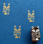 Hand carved fox wooden block stamp with golden fox impressions on deep blue handmade paper