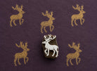 Hand-carved wooden printing block featuring a majestic stag with large antlers stamped in metallic gold ink on deep purple handmade paper.