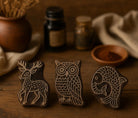 Set of three hand carved wooden printing blocks featuring Gond-inspired deer, owl and fish motifs arranged on a rustic wooden table