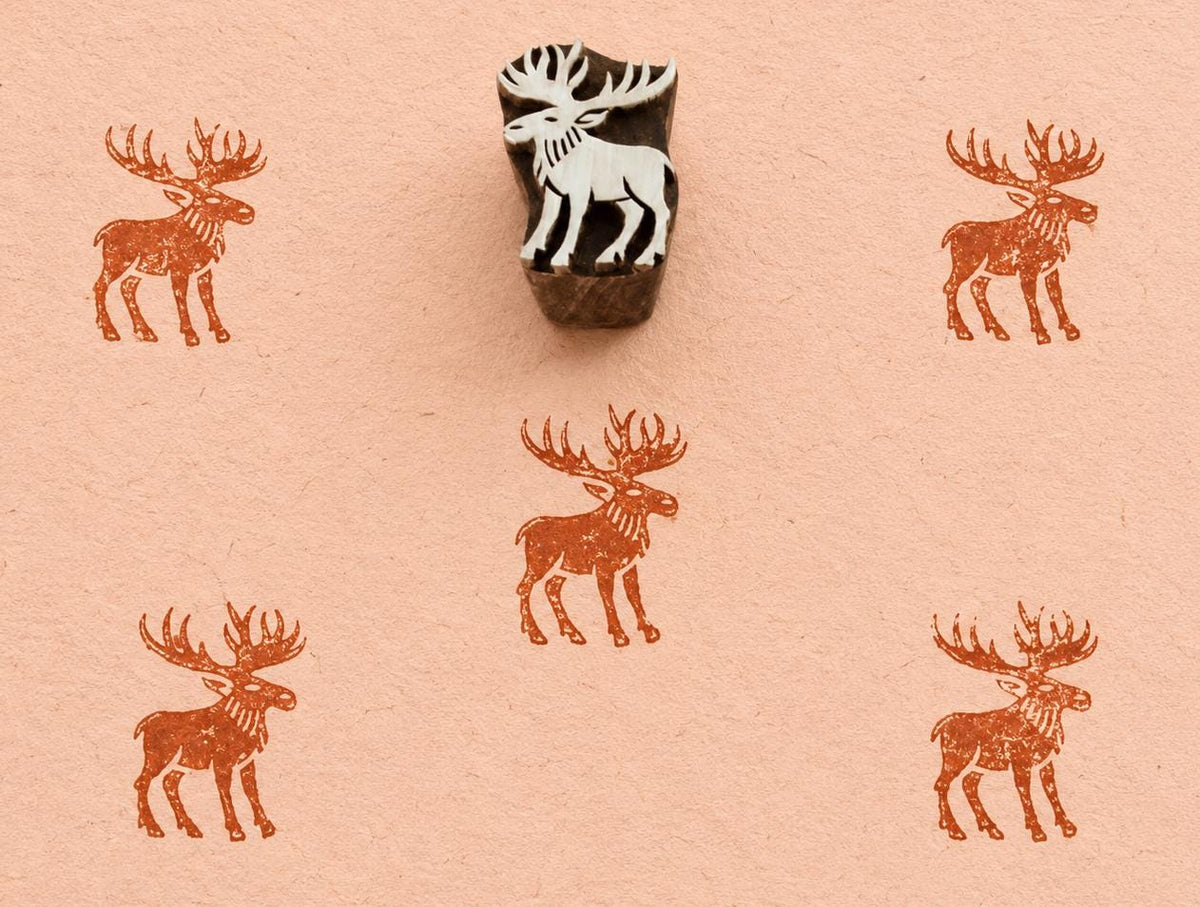 Hand carved Northern Moose wooden block stamp with rustic brown moose impressions on handmade paper.
