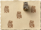 Hand carved owl block stamp creating repeated owl impressions on handmade paper.