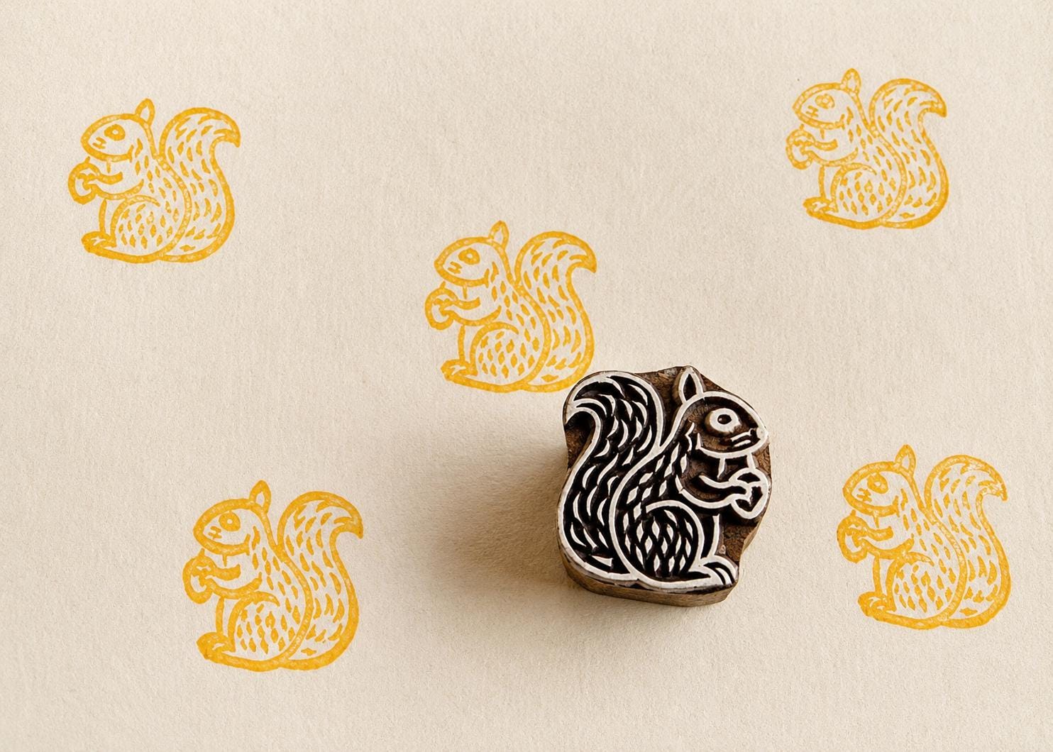 Hand carved squirrel wood block stamp printing repeating folk animal motifs on handmade paper