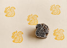 Hand carved squirrel wood block stamp printing repeating folk animal motifs on handmade paper