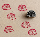 Hand carved hedgehog wood block stamp printing repeating folk animal patterns on textured paper