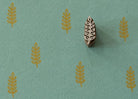 Hand carved Indian wooden printing block featuring a meadow sprig motif stamped in mustard gold on sage green handmade paper, suitable for fabric printing, pottery, clay, and paper crafts.