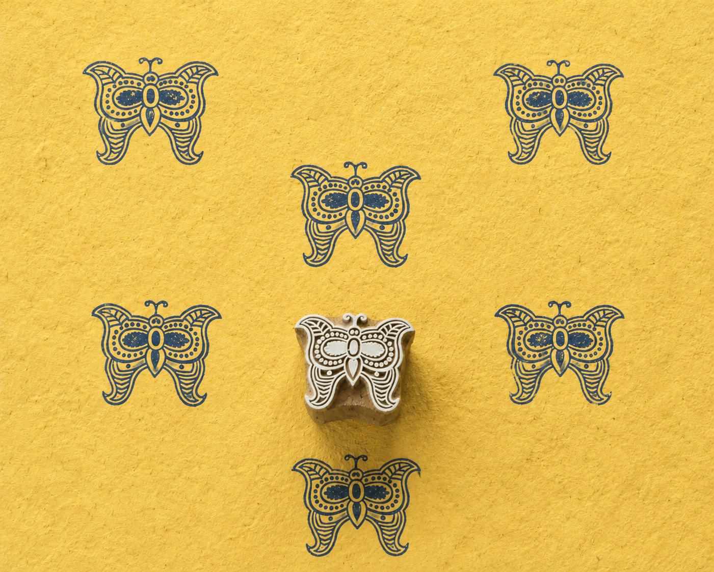 Hand carved Folk Butterfly wooden block stamp with navy blue impressions on yellow handmade paper.