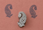 Hand-carved wooden printing block featuring a paisley flower motif with leaves, stamped in navy blue on textured terracotta handmade paper.