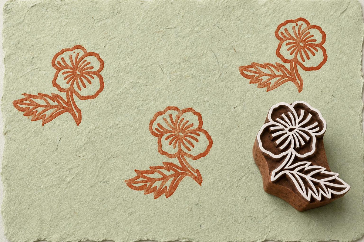 Hand carved Wildflower Bloom wooden block stamp with terracotta impressions on sage green handmade paper.