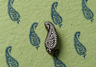 Hand carved wooden paisley printing block displayed with repeating blue floral paisley impressions on textured handmade paper.