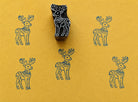 Hand carved moose block stamp creating a repeating folk animal pattern on handmade paper