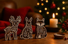 Three hand carved wooden printing blocks featuring a winter deer, rabbit and fox displayed in a cozy Christmas setting with candlelight.