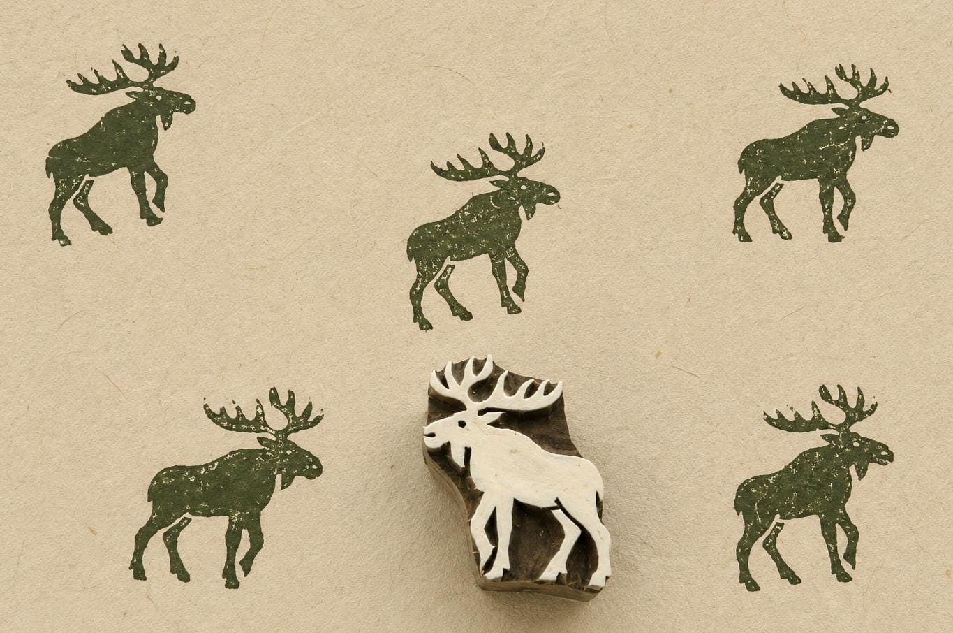 Hand carved Indian wooden printing block featuring a Nordic moose silhouette stamped in forest green on handmade paper, suitable for fabric printing, pottery decoration, clay impressions, and woodland craft projects.