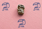 Hand carved Indian wooden printing block featuring a stylized rainforest toucan stamped in blue ink on pink handmade paper.