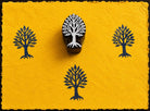 Hand carved wooden printing block featuring a sacred tree motif with blue stamped impressions on bright handmade paper.