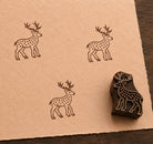 Hand carved spotted deer wooden printing block with repeated deer impressions on handmade paper