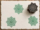 Hand carved Heritage Star Mandala wood block stamp with green geometric mandala impressions on handmade paper