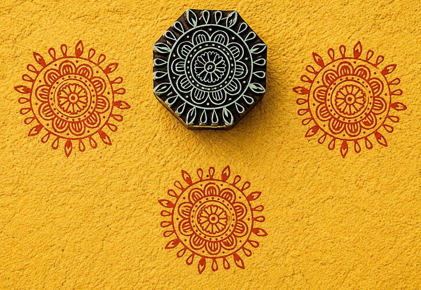 Hand carved Sunburst Mandala wood block stamp with warm terracotta mandala impressions on textured yellow paper