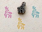 Hand carved wooden spotted deer printing block with colorful deer impressions on handmade paper.