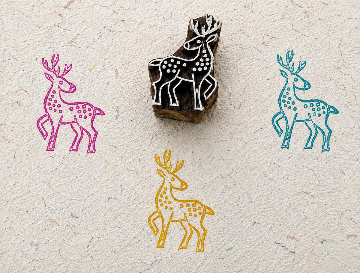 Hand carved wooden spotted deer printing block with colorful deer impressions on handmade paper.
