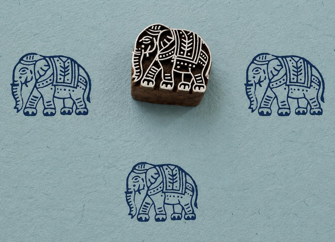 Hand carved Royal Elephant wood block stamp with blue elephant impressions on handmade textured paper