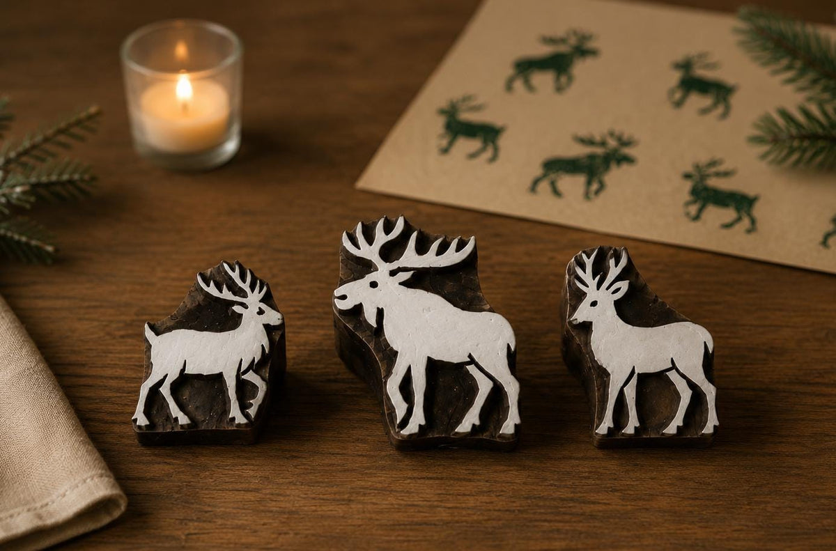 Set of three hand carved wooden printing blocks featuring Nordic moose and woodland deer designs displayed on a rustic tabletop