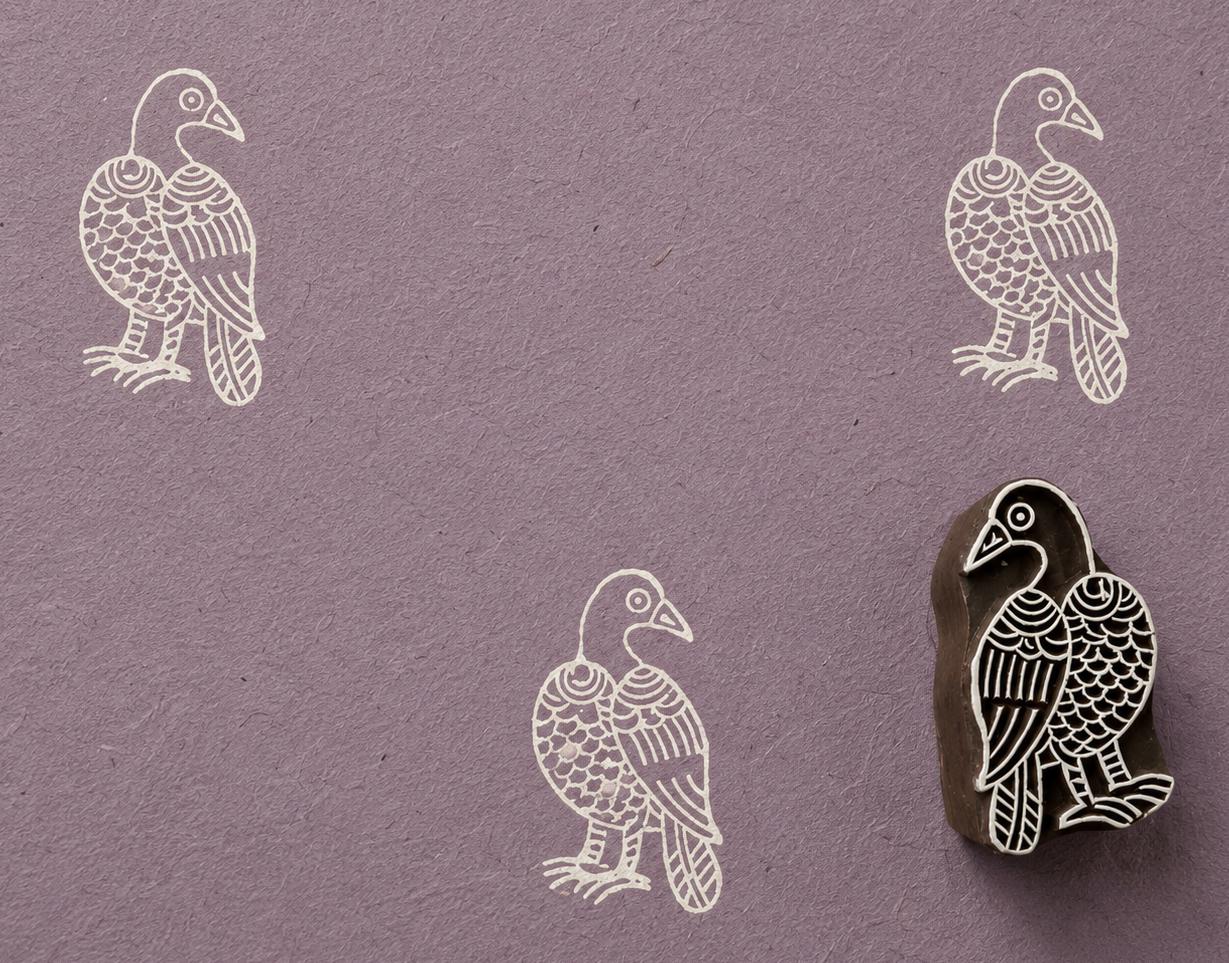 Hand carved raven wooden block stamp with ivory impressions on handmade lavender paper.
