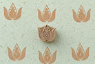 Hand-carved ornate paisley wooden printing block displayed on handmade paper with repeated decorative paisley impressions.