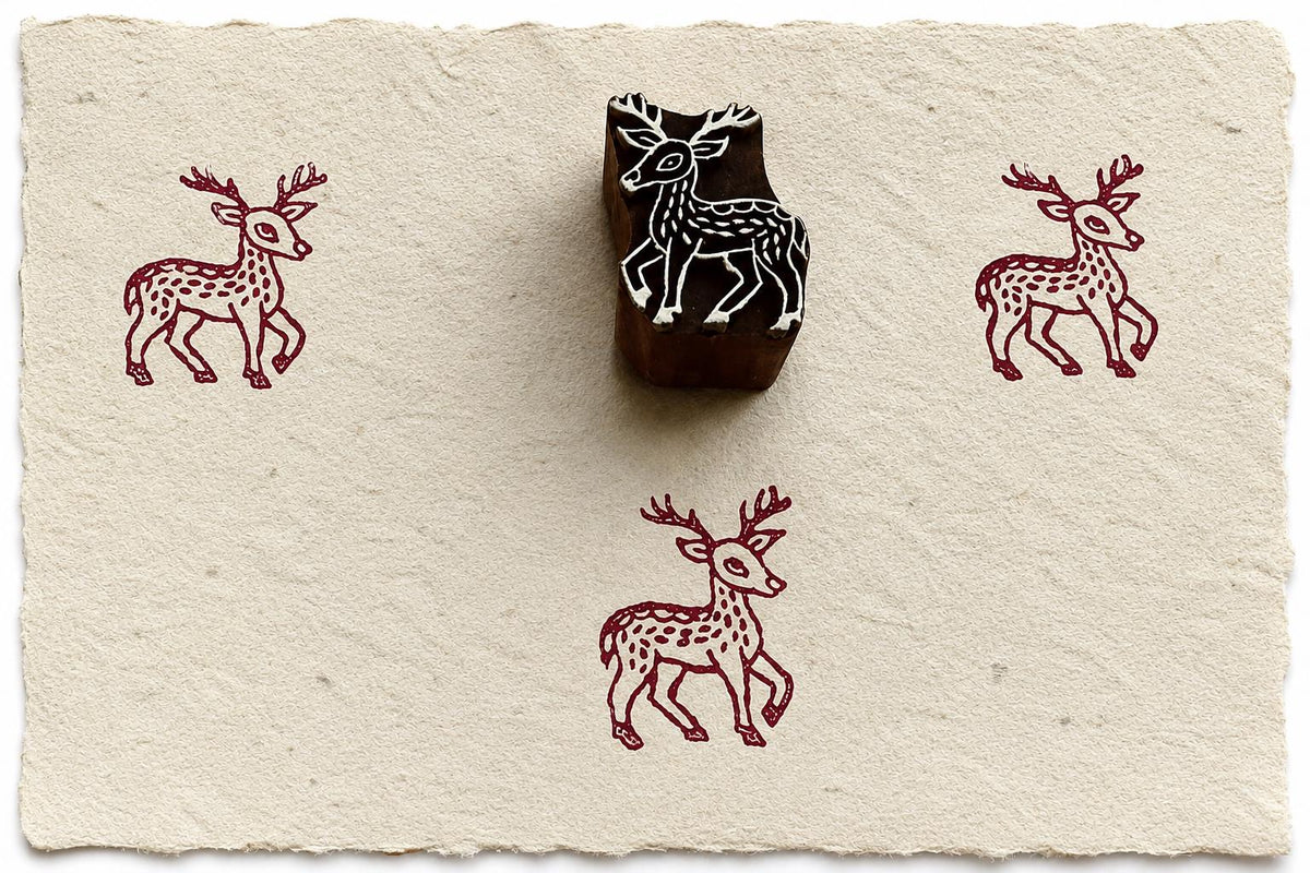 Hand carved wooden fawn block stamp with burgundy deer impressions on handmade cotton paper.
