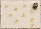 Hand carved Indian wooden printing block featuring a lily flower design, stamped in golden ochre on handmade paper, suitable for fabric printing, pottery, and paper crafts.
