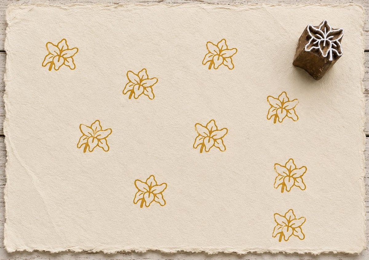 Hand carved Indian wooden printing block featuring a lily flower design, stamped in golden ochre on handmade paper, suitable for fabric printing, pottery, and paper crafts.