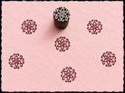 Hand-carved wooden printing block featuring an ornamental Mughal-inspired blossom motif stamped in burgundy ink on pale pink handmade paper.