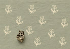 Hand carved Indian wooden printing block featuring a simple folk wildflower motif stamped on sage green handmade paper, ideal for fabric printing, pottery decoration, clay work, and paper crafts.