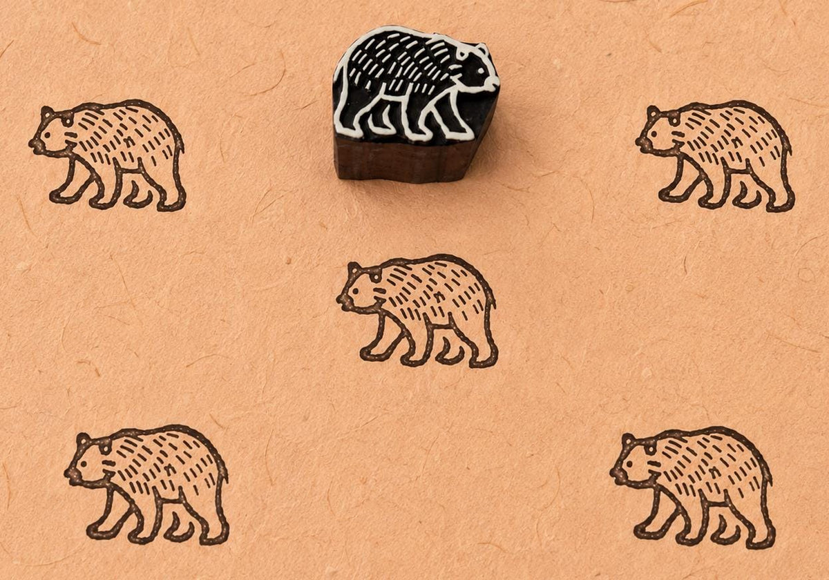 Wandering bear wooden block stamp shown with repeated bear prints on handmade paper.