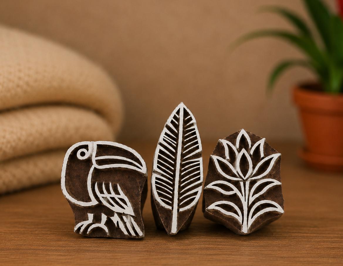 Three hand carved wooden printing blocks featuring a tropical toucan, jungle leaf, and rainforest flower displayed together as a coordinated rainforest-themed block printing set.
