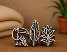 Three hand carved wooden printing blocks featuring a tropical toucan, jungle leaf, and rainforest flower displayed together as a coordinated rainforest-themed block printing set.