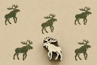 Nordic moose wooden printing block displayed beside repeated moose print impressions on handmade paper